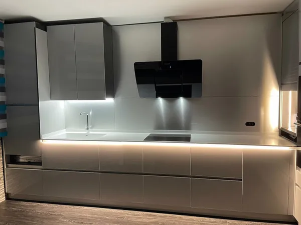 Cocina gris en brillo con campana negra decorativa y tiras de luz led bajo la encimera y los muebles altos: cocina montada por Kitchenmania en Borox (Toledo)