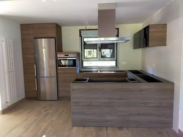 Cocina en madera de roble con isla, campana de isla de acero y frigorífico de acero: cocina montada por Kitchenmania en Sacedón (Guadalajara)