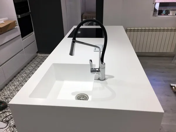Isla blanca con fregadero integrado en la encimera y grifo extraíble negro, suelo hidráulico: cocina montada por Kitchenmania en San Sebastián de los Reyes