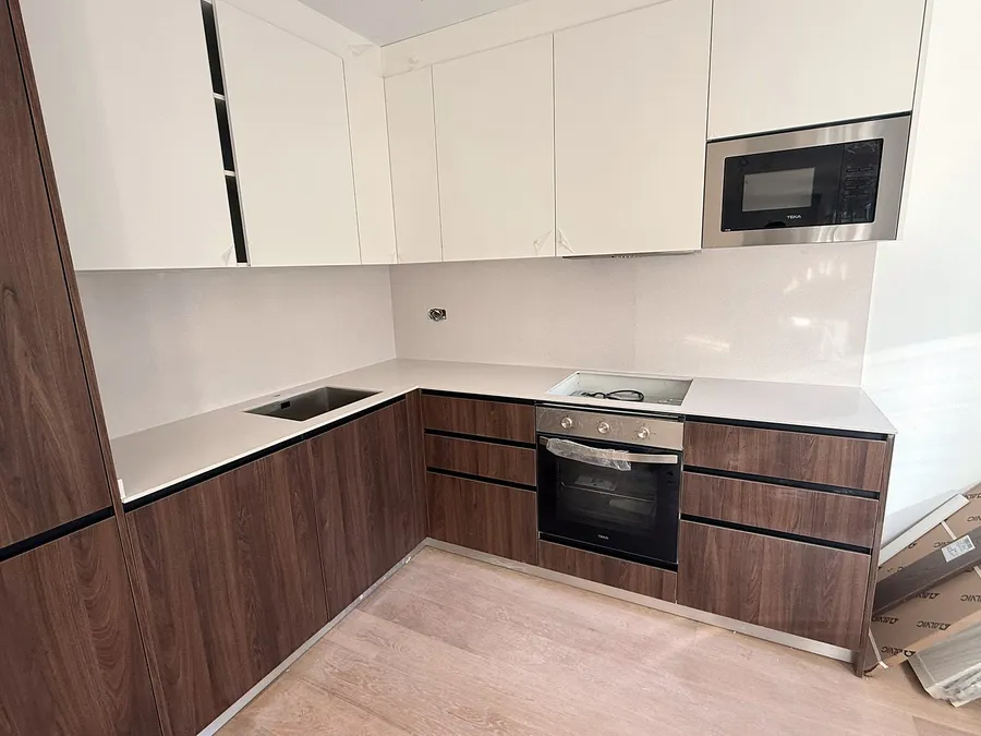 Cocina en L con encimera de cuarzo compacto Silestone Blanco Norte pulido, bajos de nogal y altos blancos: encimera montada por Kitchenmania